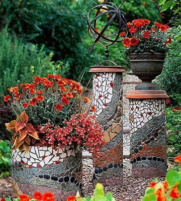 three pots with flowers in them sitting on the ground next to some bushes and trees