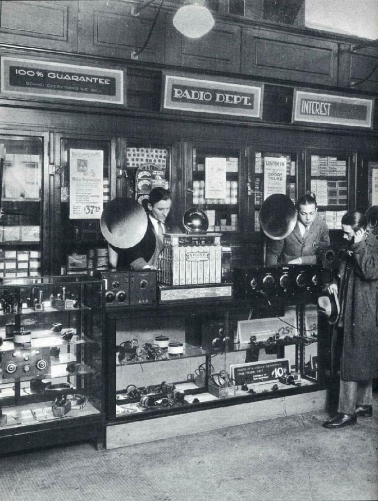 an old black and white photo of people looking at various items in a store window