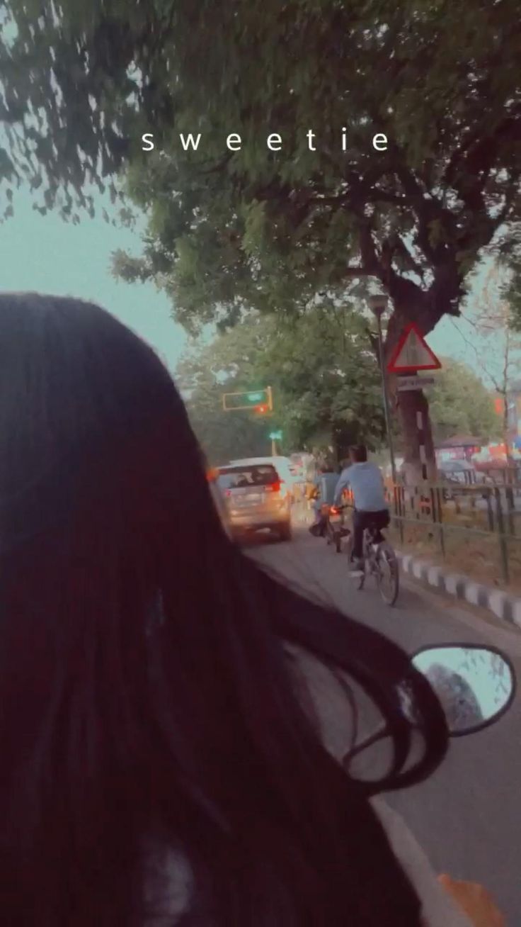 a woman riding a bike down a street next to a traffic filled road with cars