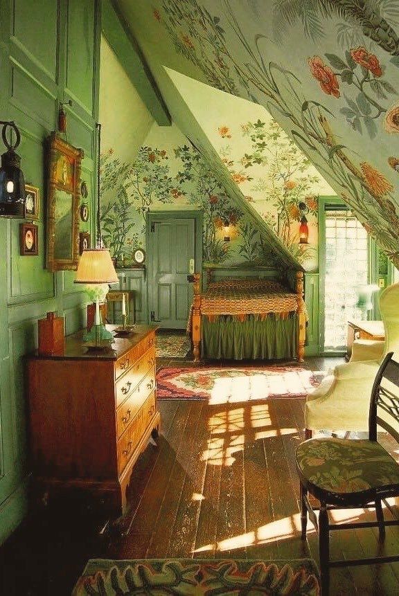 an attic bedroom with green painted walls and floral wallpaper on the ceiling, along with antique furniture