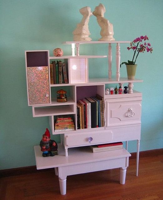 there is a white shelf with books on it and a small table in front of it