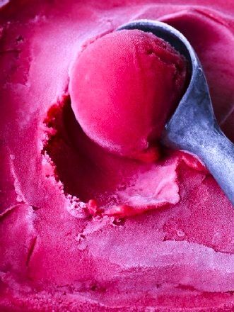 a spoon full of pink ice cream on top of a table next to some color swatches