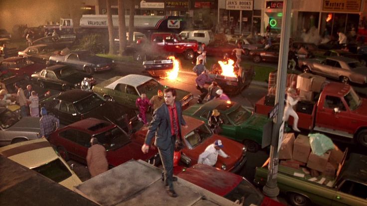 a man standing in the middle of a parking lot with lots of cars on it