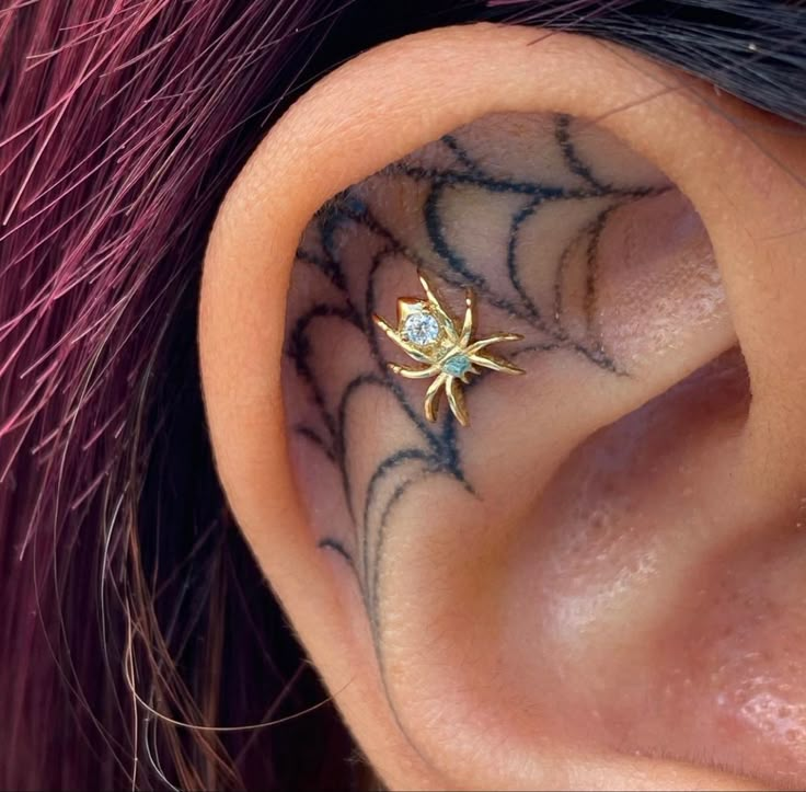 a close up of a person's ear with a spider tattoo on it