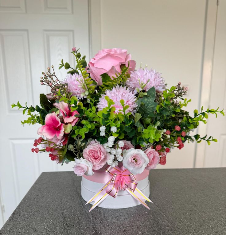 a bouquet of pink flowers in a white container