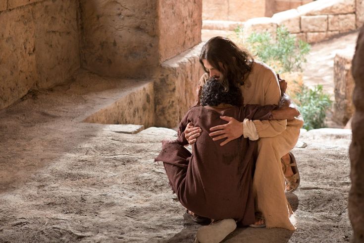 a man sitting on the ground with his arms wrapped around him