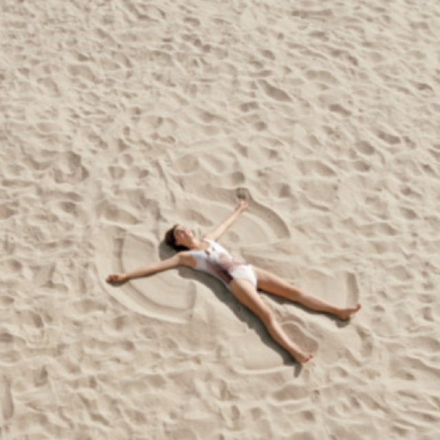 a woman laying on top of a sandy beach next to the words, enjoy summer