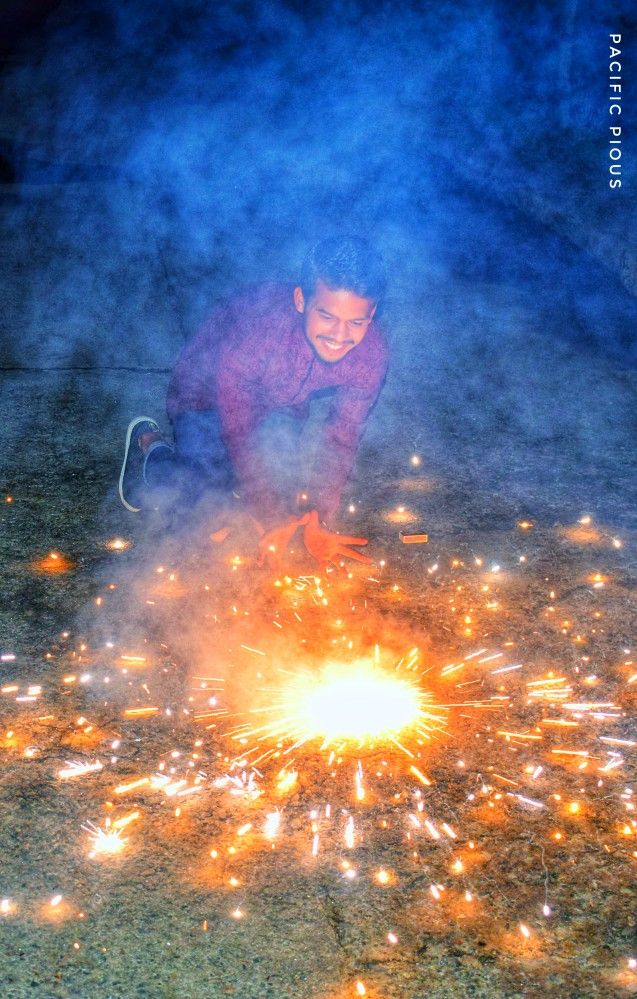 a man kneeling down in front of a fire with lots of sparkles on it