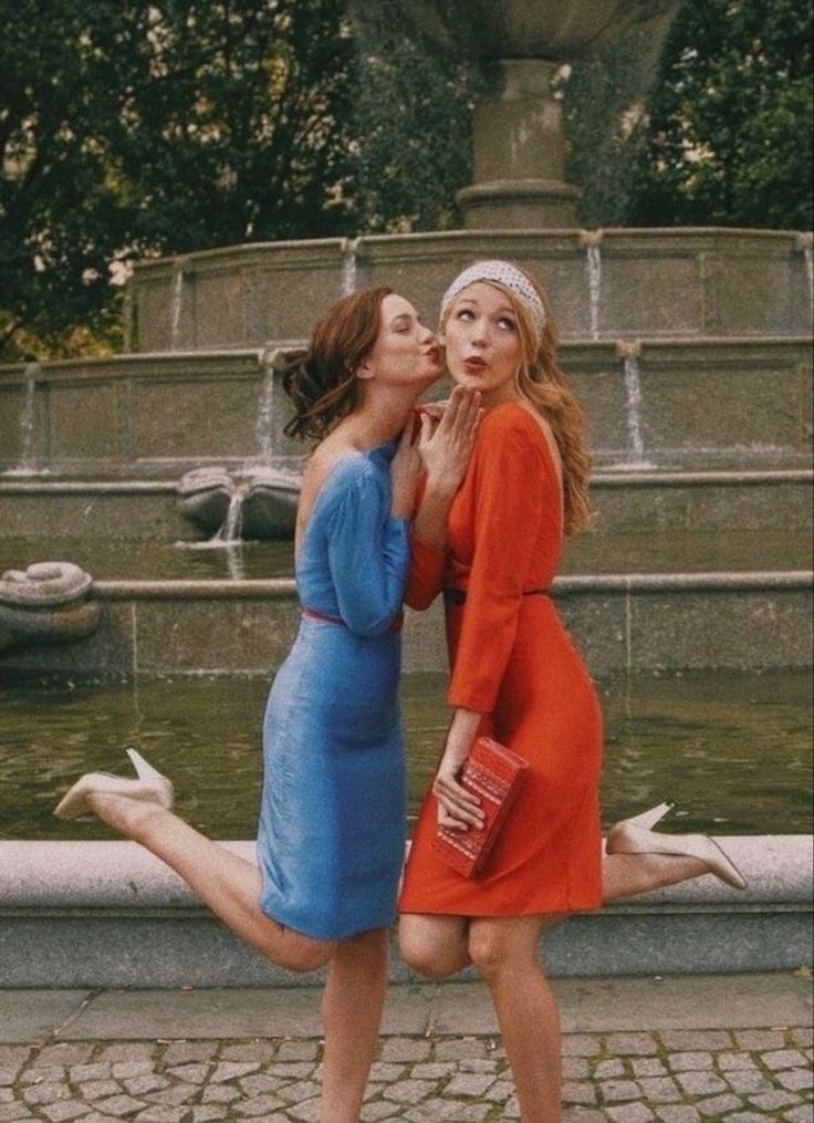 two women kissing each other in front of a fountain