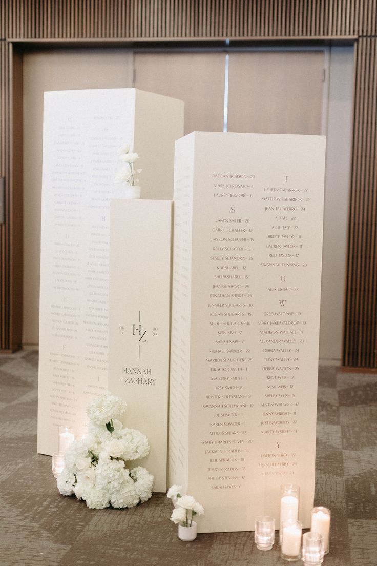 white flowers and candles are sitting on the floor next to two folded up menus