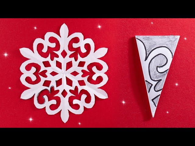 an origami snowflake cut out from paper and placed on a red background