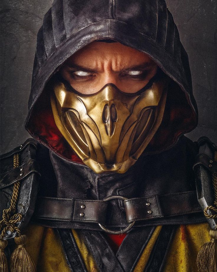 a man wearing a hood and mask with his eyes closed, in front of a dark background