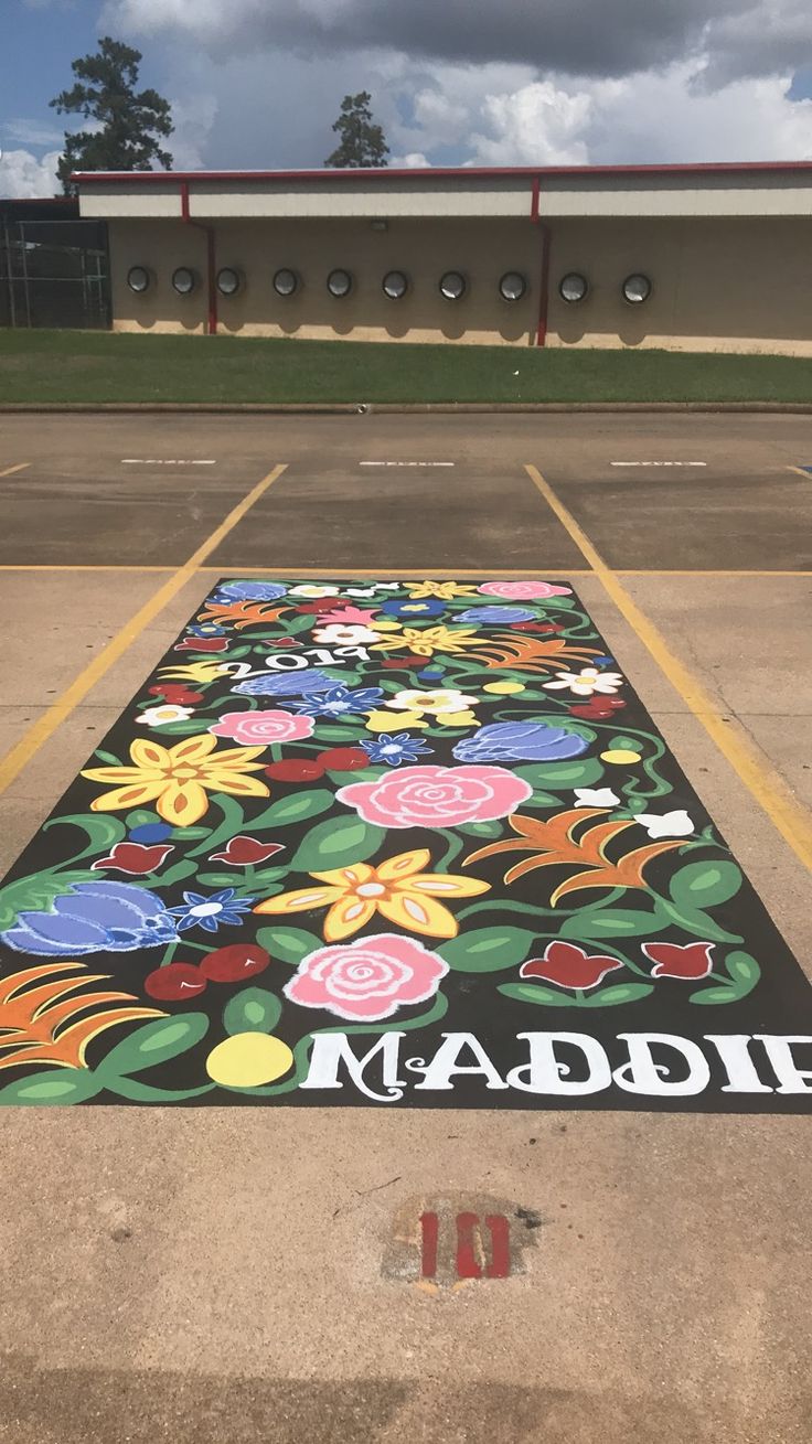 the parking lot has been painted with flowers and leaves on it, along with an inscription made in large letters