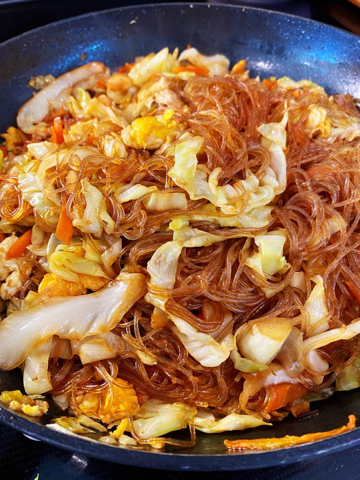 a pan filled with noodles and vegetables on top of a stove