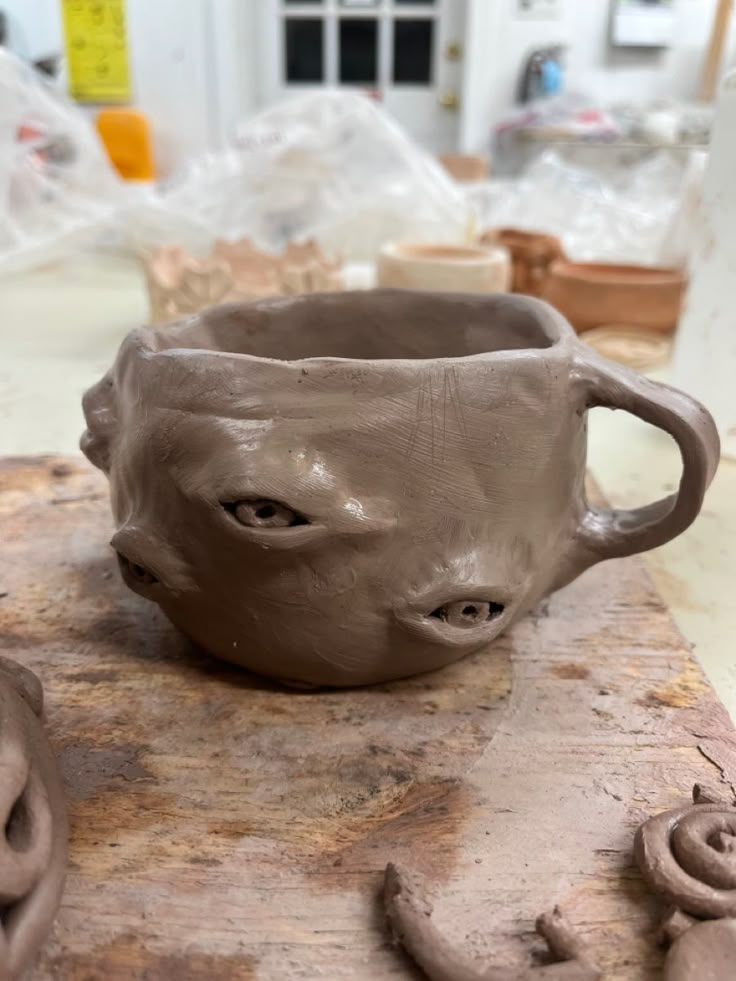 a clay cup sitting on top of a wooden table