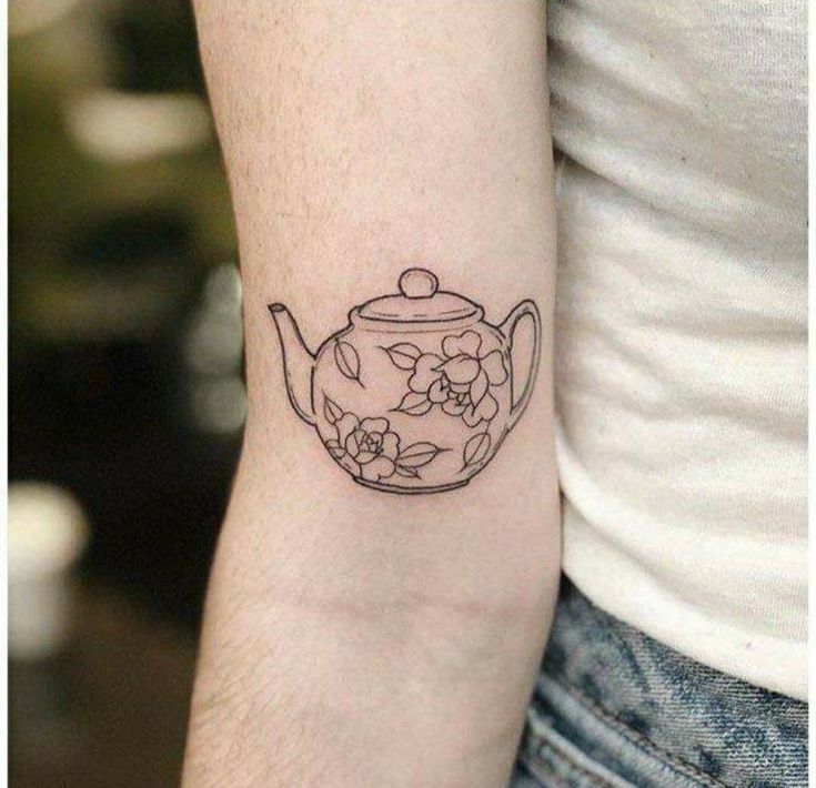 a black and white photo of a teapot tattoo on the left arm with flowers in it