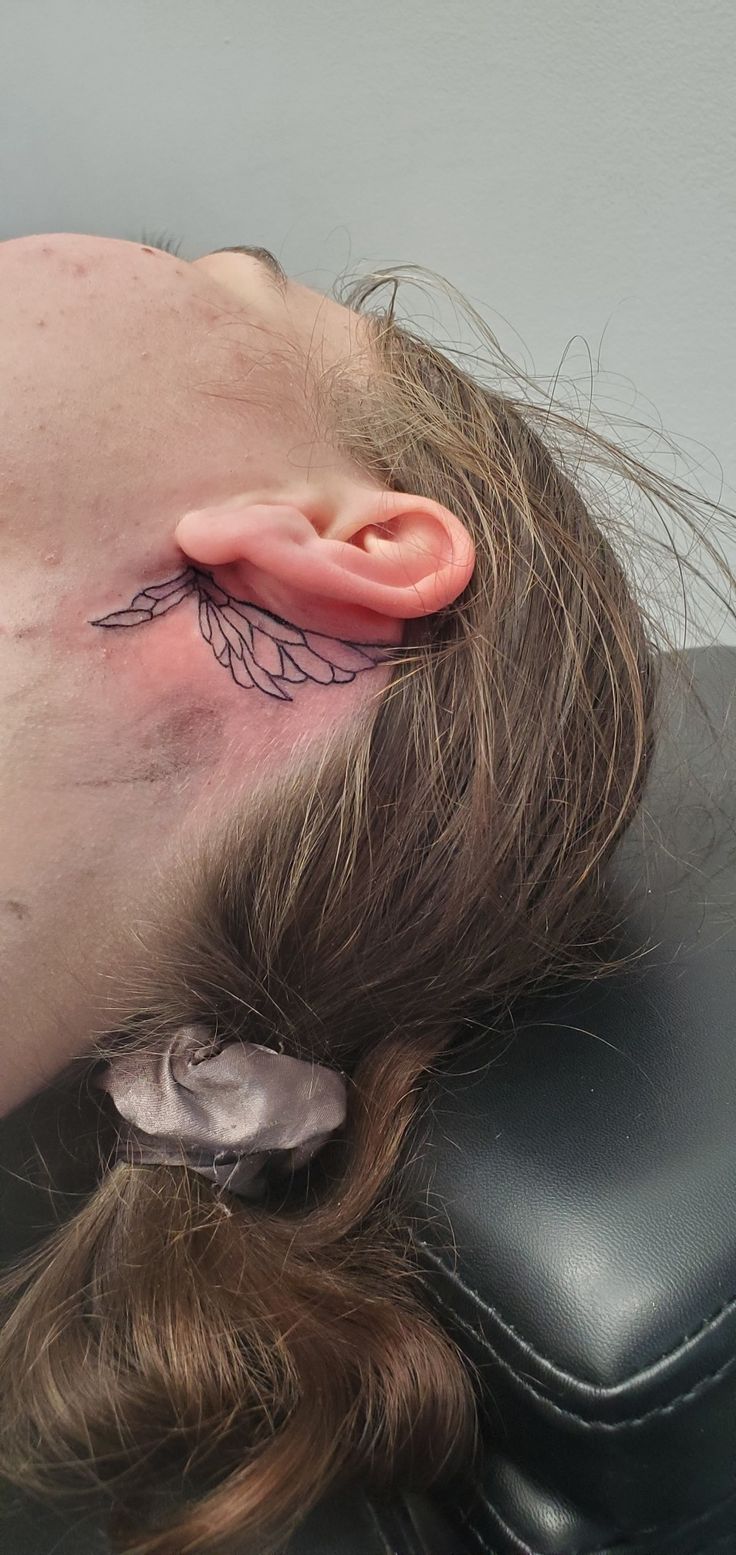 a man with a tattoo on his forehead is laying down in a black leather chair