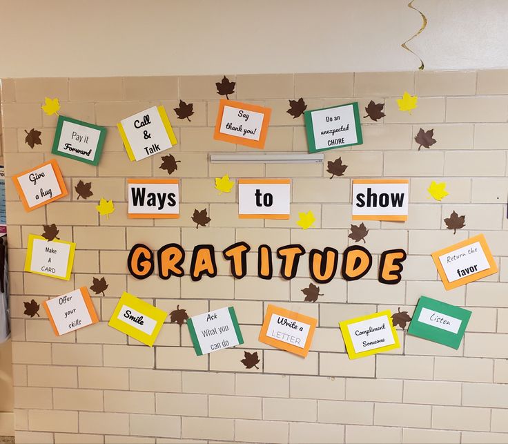 a bulletin board with the words, ways to show gratitude and leaves on it in front of a white brick wall