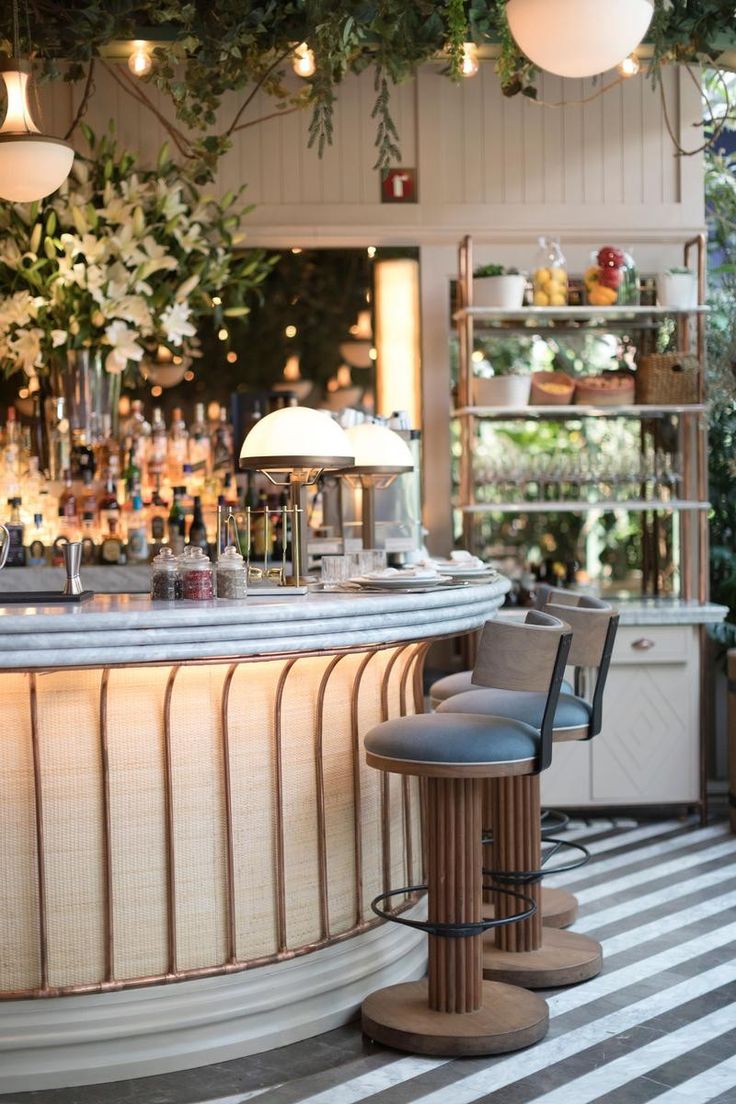 a bar with two stools in front of it and lights hanging from the ceiling