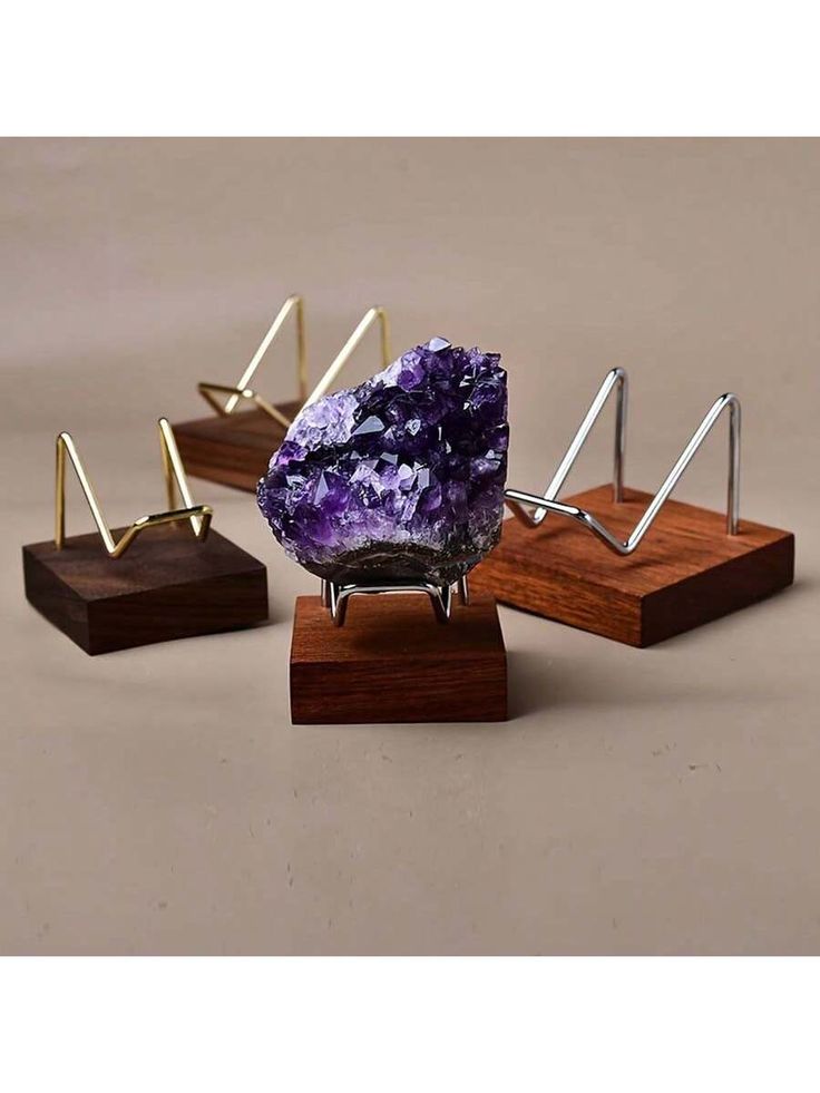 three different types of ametholite displayed on wooden stands with metal rods and wood bases