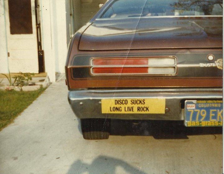 an old car parked in front of a house with a license plate on it's bumper