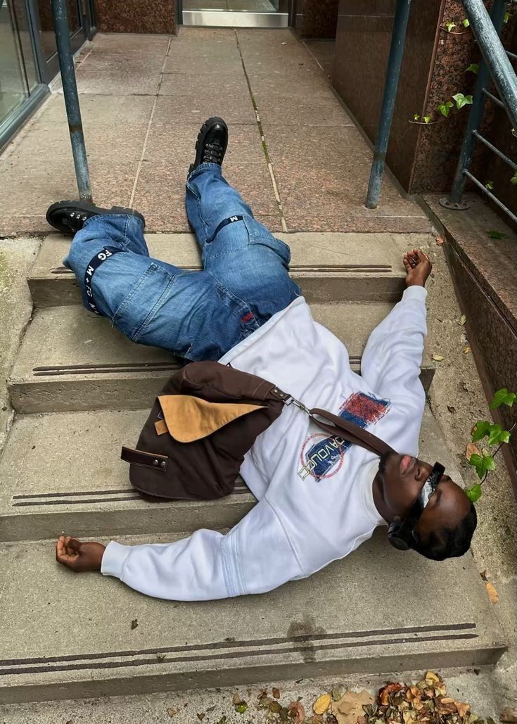 a man laying on the steps with his feet up and one hand in the air