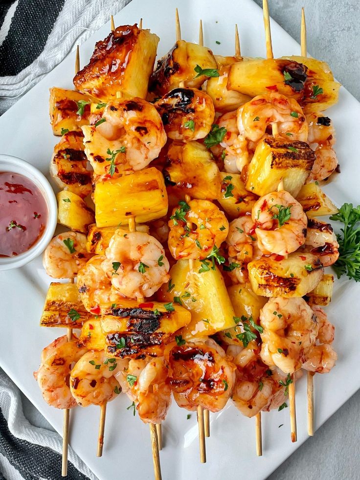 grilled shrimp and pineapple skewers with ketchup on a white plate