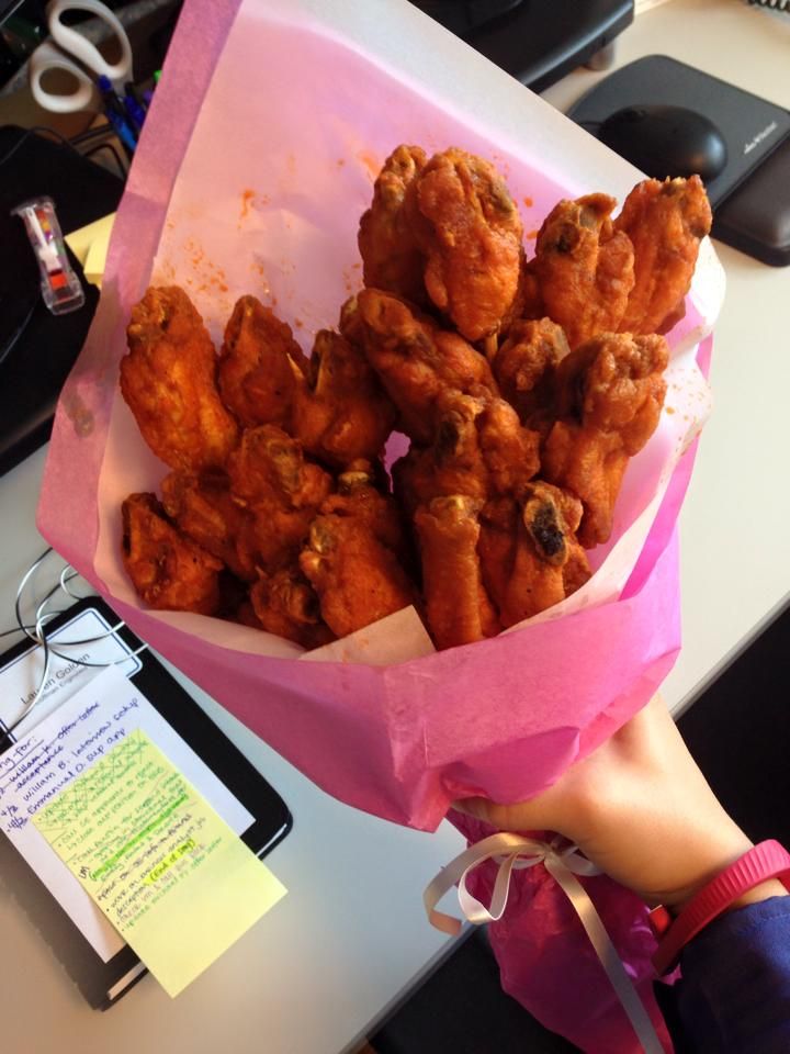 a pink paper bag filled with fried food on top of a white table next to a computer