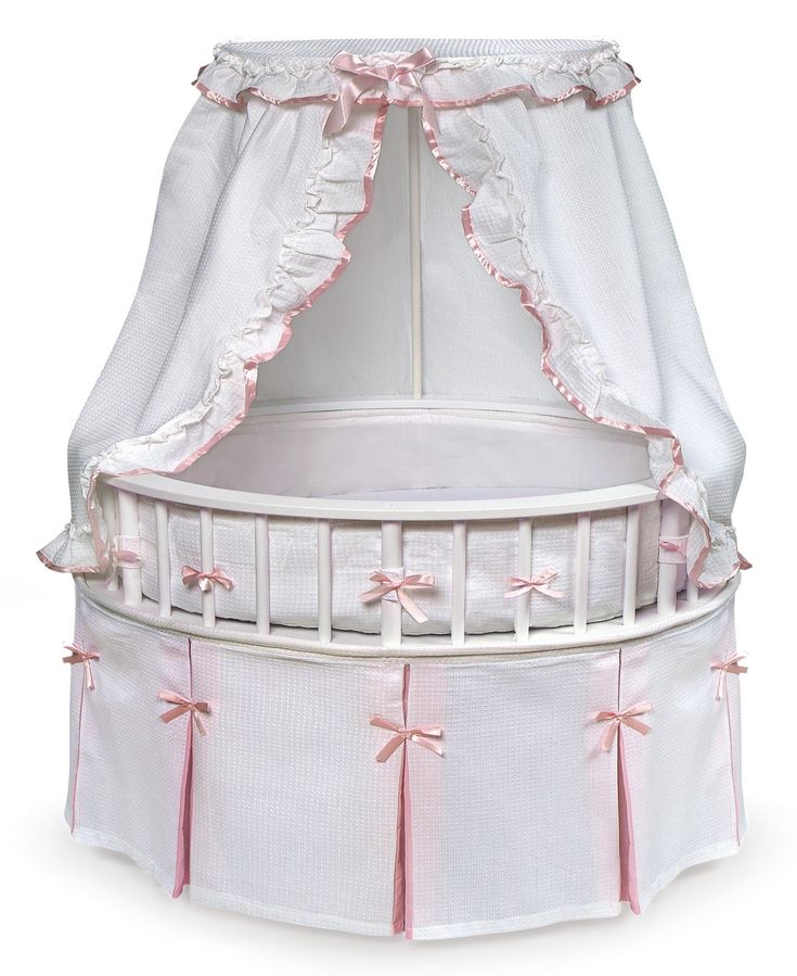 a white crib with pink bows on the top and bottom, in front of a white background