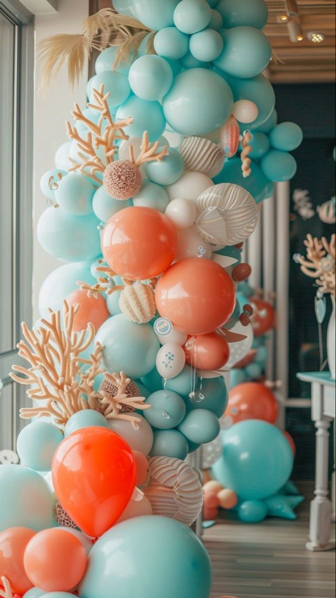 balloons are hanging from the ceiling in an ocean themed room with corals and seashells