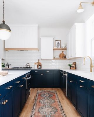 a kitchen with dark blue cabinets and white counter tops, an area rug in the middle