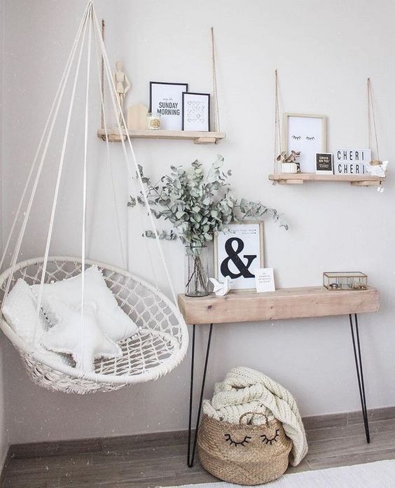 a white hammock hanging from a wall next to a wooden table and shelf