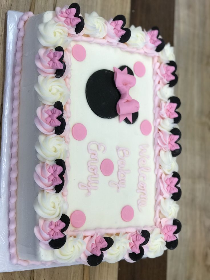 a minnie mouse birthday cake with pink and white frosting on it's side