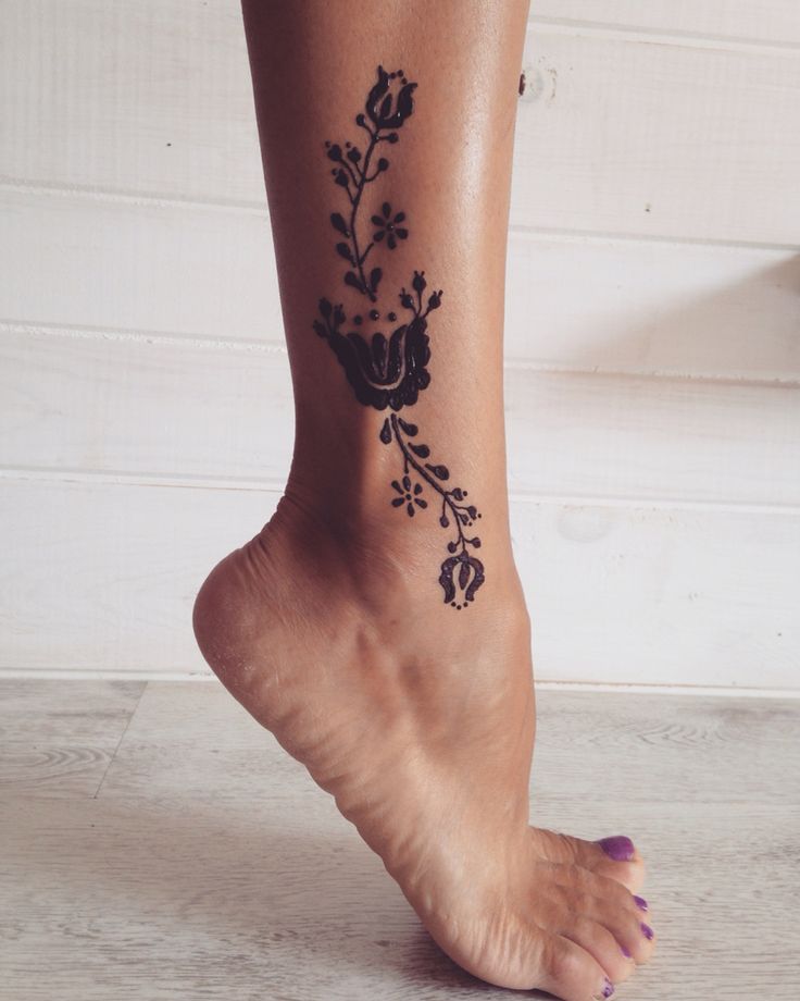 a woman's foot with a flower tattoo on the bottom of her left leg