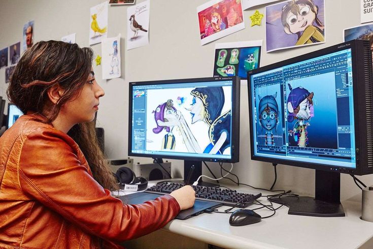 a woman sitting in front of two computer monitors