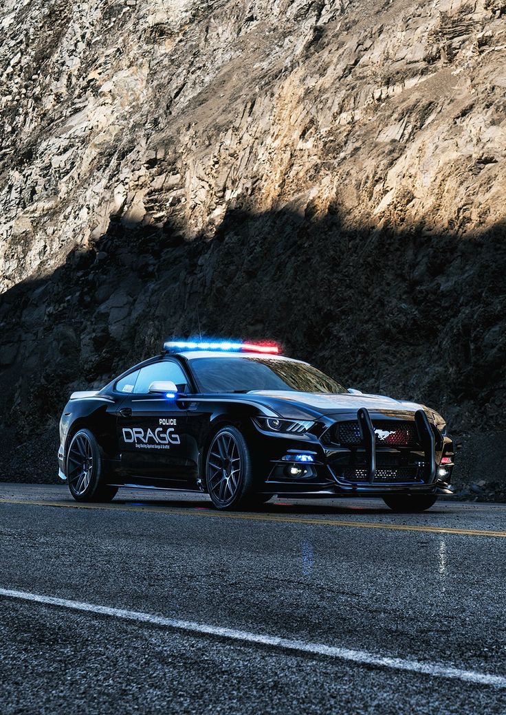 a police car is parked on the side of the road near a mountain with its lights on