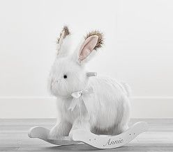 a white rabbit sitting on top of a wooden rocking toy with ears and tail curled up