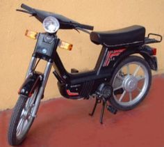 a black motorcycle parked next to a yellow and brown wall with red trimmings