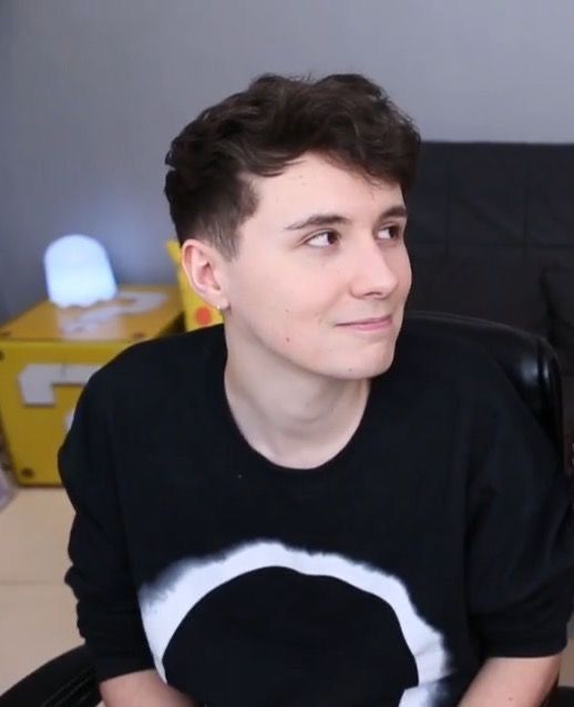 a young man sitting in a chair holding a remote control