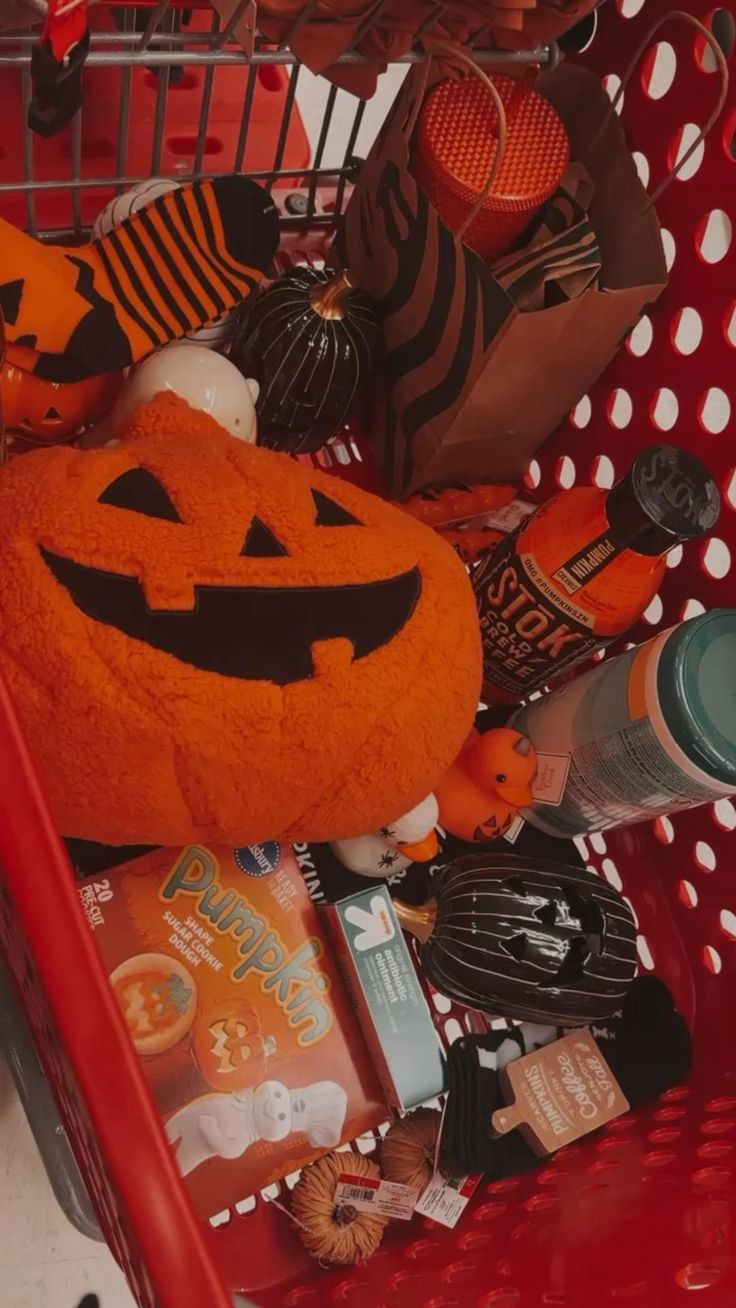 a shopping cart filled with halloween items including a jack - o'- lantern stuffed animal