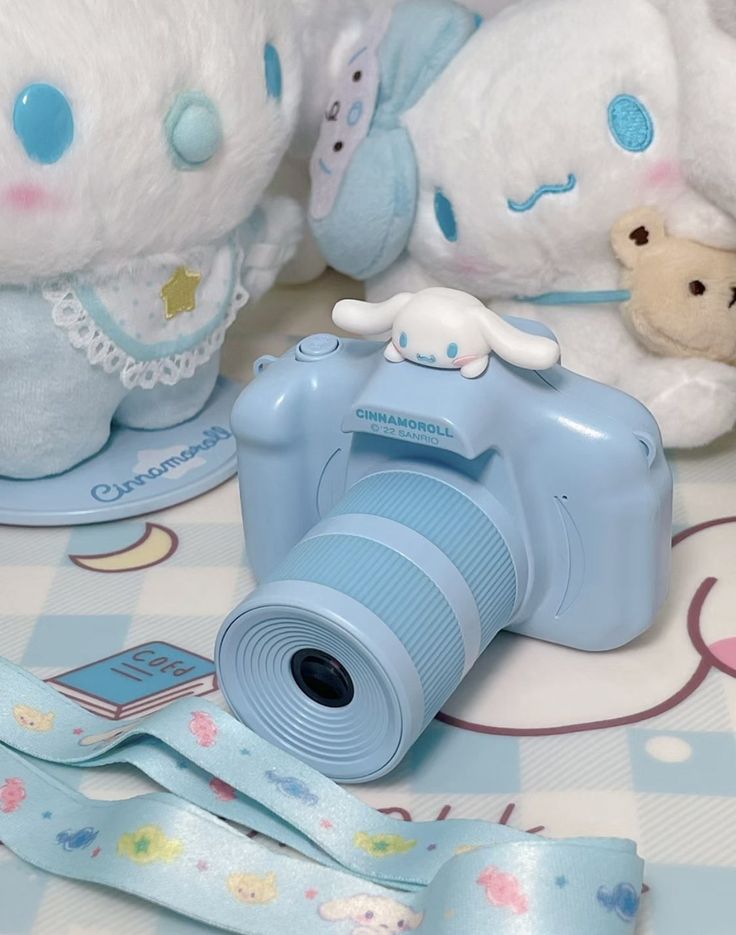 a blue camera sitting on top of a table next to stuffed animals