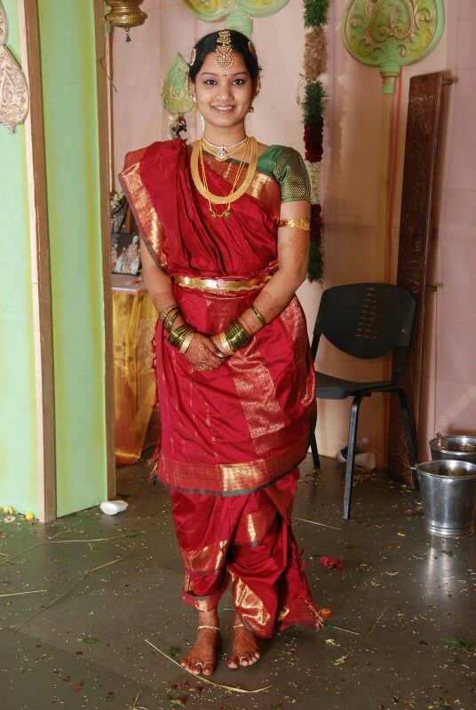 a woman in a red and gold sari standing with her hands on her hips