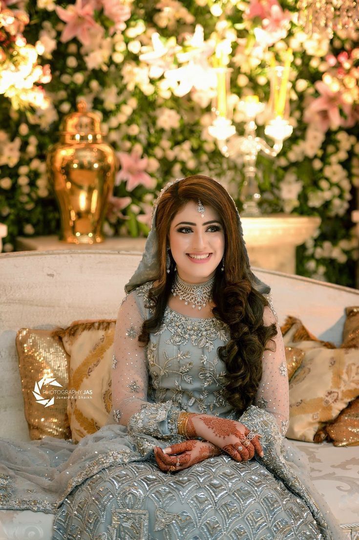 a woman sitting on top of a white couch in front of a flower covered wall