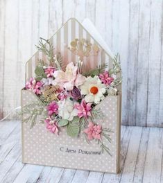 a close up of a card with flowers in it on a wooden table next to a white wall