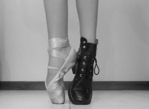 black and white photograph of woman's feet with shoes tied to each other on the floor