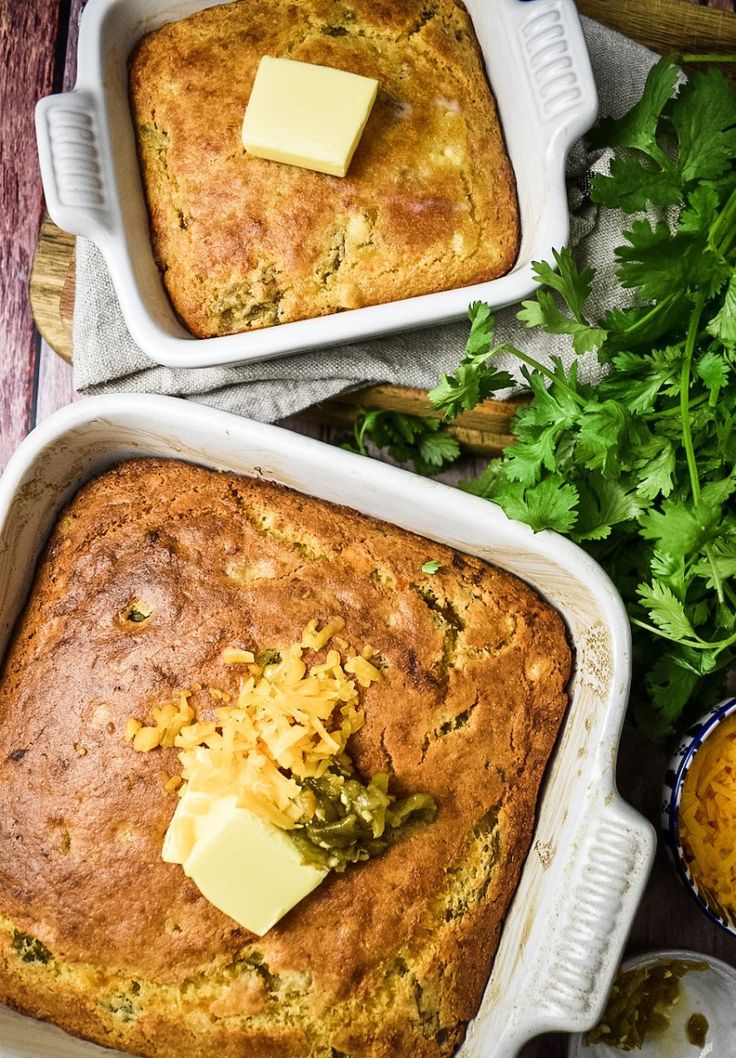 two loafs of bread with butter and parsley in them on a wooden table