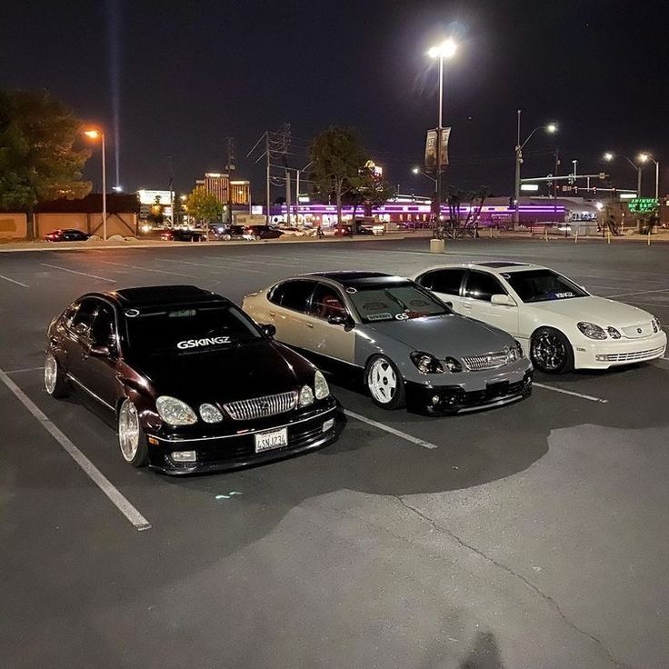 three cars parked in a parking lot at night