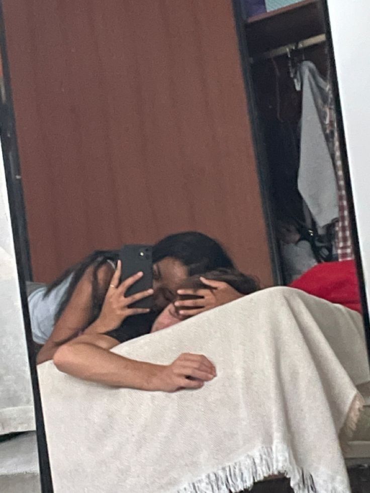 two people are taking pictures in the mirror with their cell phones and one person is covering her face