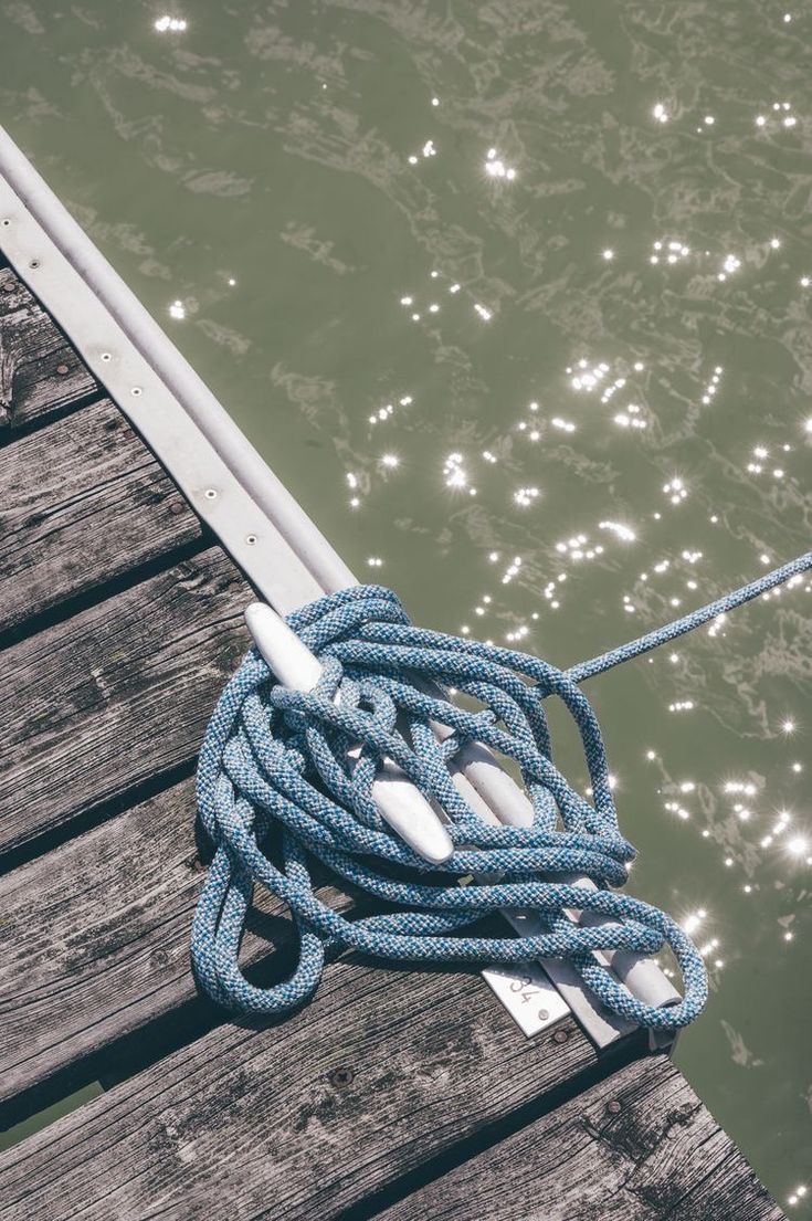 a blue rope tied to the end of a dock next to water and wooden planks