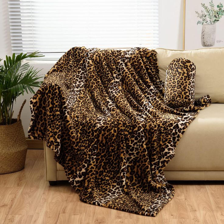 a leopard print blanket on a couch next to a potted plant